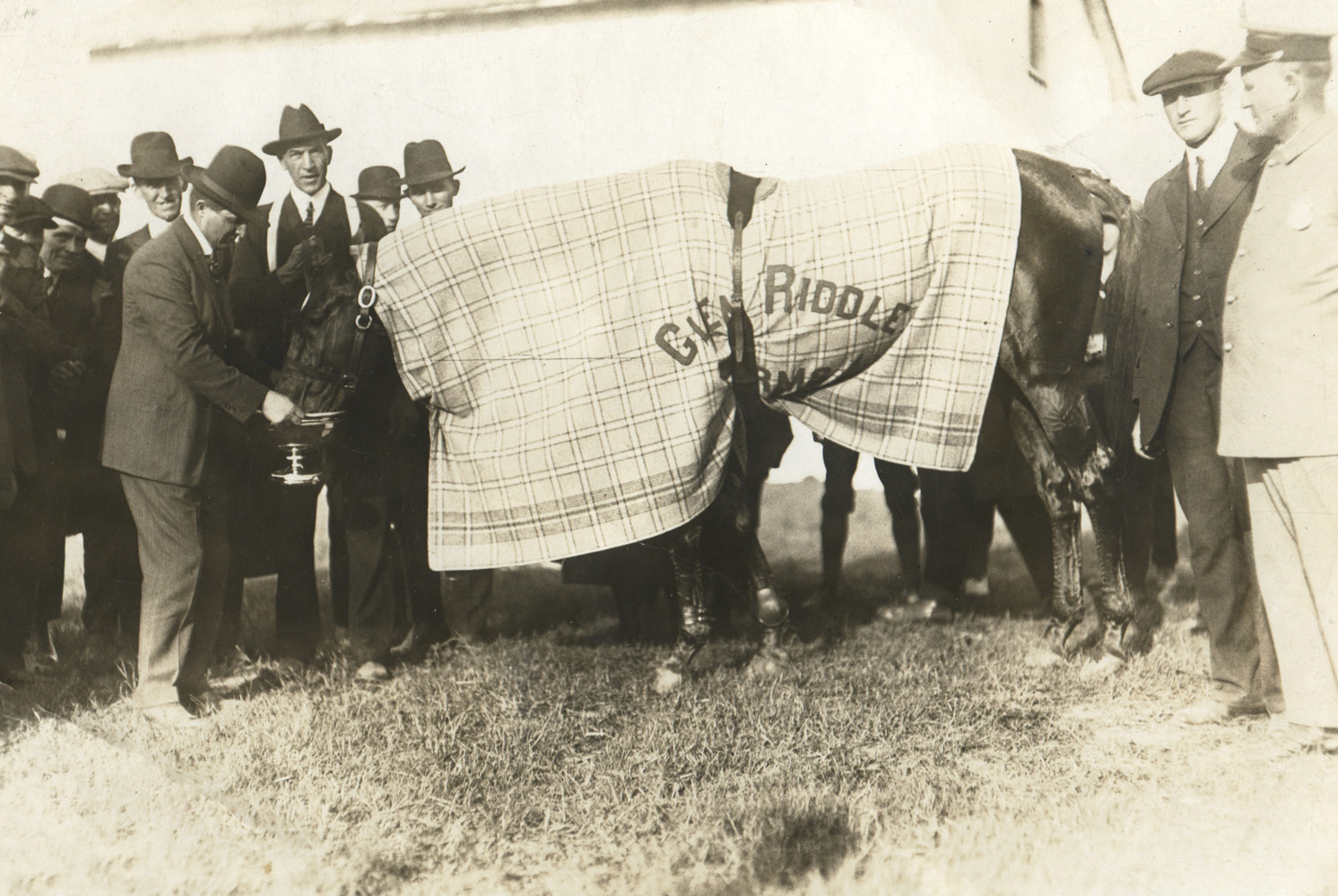 Louis Feustel holds the Kenilworth Gold Cup trophy as Man o' War drinks from it to celebrate his win in the match race against Sir Barton (Museum Collection)